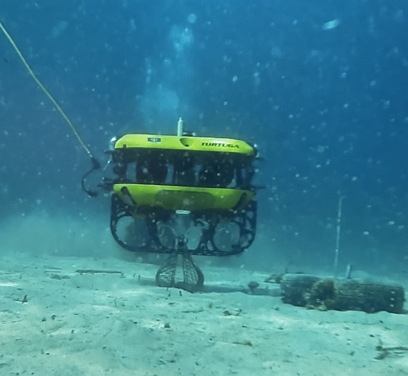 The Tortuga robot collecting a bottle from the seafloor.