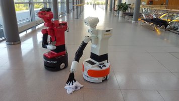 One robot picks up an object from the floor. 